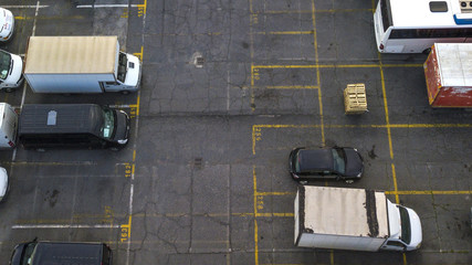 Naklejka premium Aerial view of a large parking lot for cars, trucks, motorcycles and caravans. The lines of the parking lots are yellow and there are still many free places on the asphalt.