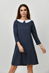 Young beautiful woman posing in new casual winter dotted blue dress on grey 