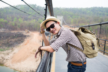 Young man traveller backpacker on rope bridge.