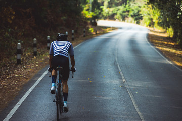 Asian men are cycling road bike in the morning.He is on a forest road.