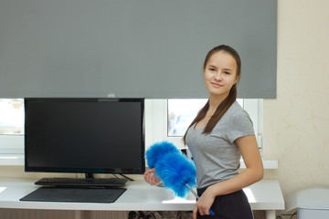 Apartment cleaning.Young European girl with long hair cleans up dust brush at home