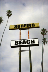 Fototapeta premium aged and worn surfing beach sign with palm trees