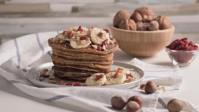Healthy breakfast table,  homemade pancakes with banana, goji and walnuts.
