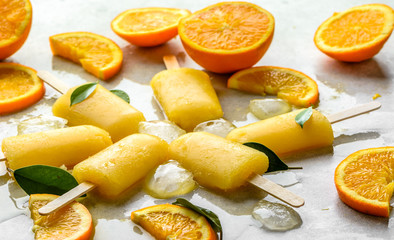 Orange popsicles with frozen juice and ice cubes, summer refreshing snack