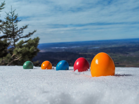 painted easter eggs laying in the snow on top of a mountain in a line