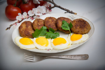 Meatballs and eggs with tomato, bread and greens