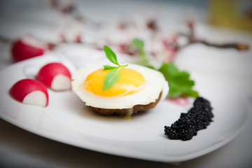 Meatball and egg on with black caviar on white plate