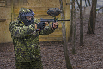 Fototapeta premium Paintball player takes aim, hides and shooting. Man wearing protective equipment