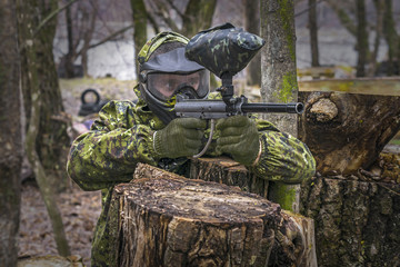 Paintball player takes aim, hides and shooting. Man wearing protective equipment