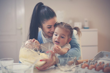 Obraz na płótnie Canvas Young mother and daughter baking cookie and mixing dough.