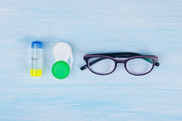 glasses and objects for cleaning and storing contact lenses, to improve vision, on a blue background