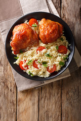 Homemade food: baked chicken thighs with garnish of rice close up. Vertical top view from above