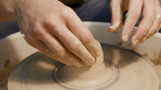 Male craftsperson sculpt process on the round potterswheel closeup isolated. Artisan dexterity creating product - cup or vase from wet brown mud. Lifestyle, leisure, creativity concept of background
