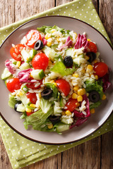 Tasty salad of fresh vegetables, rice and lettuce close-up on a plate. Vertical top view from above
