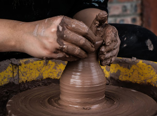 hands of a potter, creating an earthen jar on the circle
