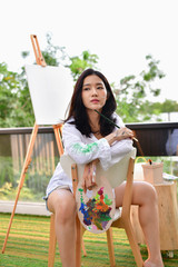 Concept Artist Beautiful girl. Beautiful women are creating art. Beautiful woman is painting happily. Young artist painting outside the house.