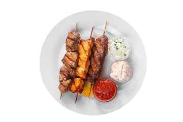 Shish kebab, beef, lamb, pork, chicken meat on the grill, barbecue, without garnish on a plate isolated on white background. Marinated onion, mayonnaise, tar tar, ketchup, tomato sauce View from above