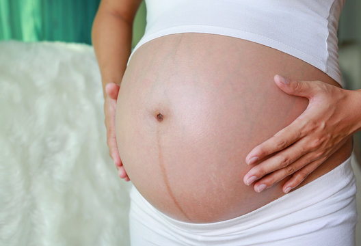 Pregnant Woman holding her hands on her belly.