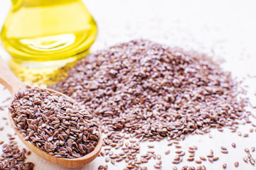 flax seeds in a wooden spoon, next flaxseed oil, on an old board