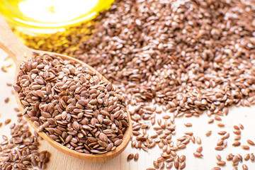 flax seeds in a wooden spoon, next flaxseed oil, on an old board