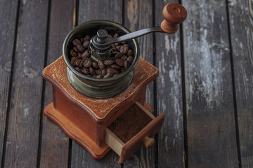 on a dark wooden table a coffee grinder and coffee beans in it