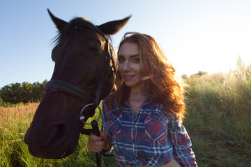 Fototapeta premium Young attractive woman and horse in the meadow at summer evening