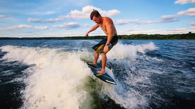 Healthy Young Active Male Wake Surfing Behind Boat on Sunny Summer Afternoon