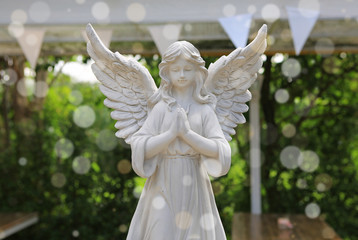 Sculpture of an angel in the garden with bokeh.