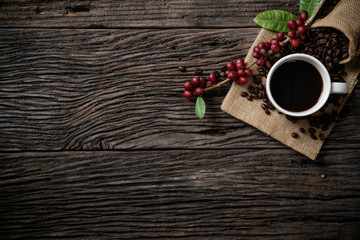 Top view mockup a cup of coffee and coffee beans in the sack on the wooden desk.