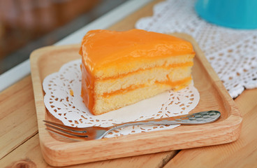 Orange cake in wooden plate at the cafe.
