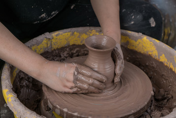 hands of a potter, creating an earthen jar on the circle
