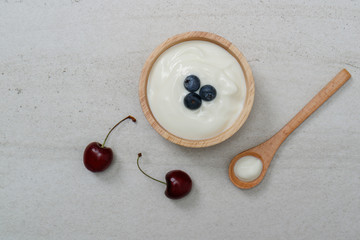 Yogurt in wooden bowl with fresh blueberries and cherry.Top view