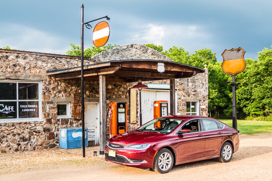 Colorful old style gas station with the car. Old style gas station with ancient pumps under the stormy skyline with refilling car.