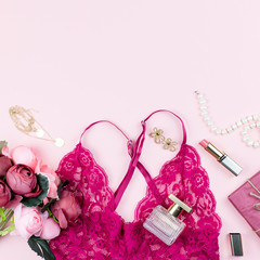 Woman fashion accessories, make up products and red lingerie on pastel background.