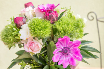 Large beautiful pink bouquet of peonies, roses, anemones, white freesia in a vase on green background. Spring flowers concept.