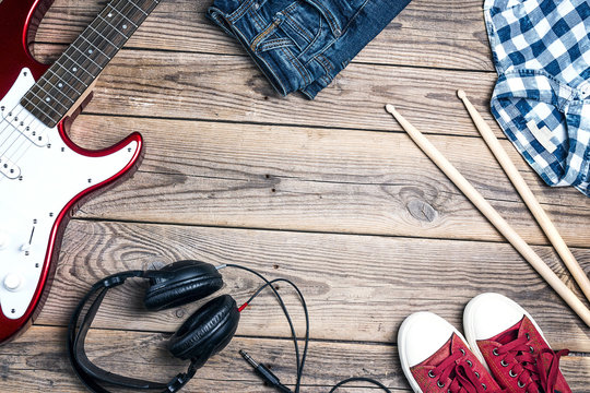 Music equipment, clothes and footwear on wooden background with copy space.