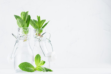 Transparent lemonade with mint sprig in vintage bottles on soft white wood background. Summer fresh beverage.