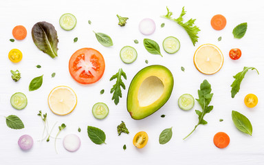 Food pattern with raw ingredients of salad. Various vegetables lettuce leaves, cucumbers, tomatoes, carrots, broccoli, onion and lemon flat lay on white background.