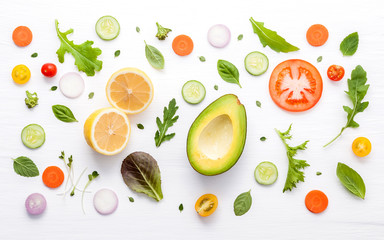 Food pattern with raw ingredients of salad. Various vegetables lettuce leaves, cucumbers, tomatoes, carrots, broccoli, onion and lemon flat lay on white background.