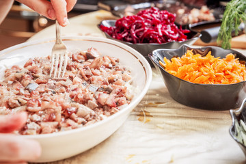 preparing russian traditional salad 'herring under fur coat'