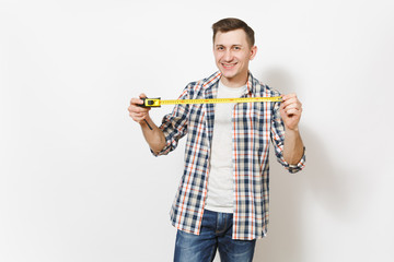 Young smiling handsome man in casual clothes holding measure tape isolated on white background. Instruments, accessories, tools for renovation apartment room. Repair home concept. Advertising area.