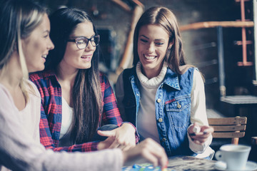 Fototapeta premium Three cheerful girls playing board game.