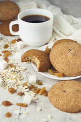 Cup of Black Coffee in a White cup, Oatmeal cookies, oatmeal, raisins on a light background. Breakfast Scene
