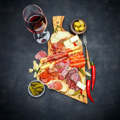meat and cheese plate and wine with sausage, prosciutto, olives