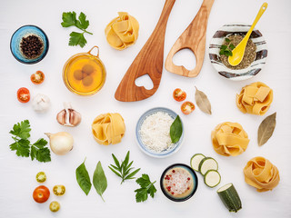 Italian foods concept and menu design. Dried homemade Fettuccine with heart shaped wooden spatula and  ingredients sweet basil ,tomato ,garlic ,parsley ,and parmesan cheese flat lay.