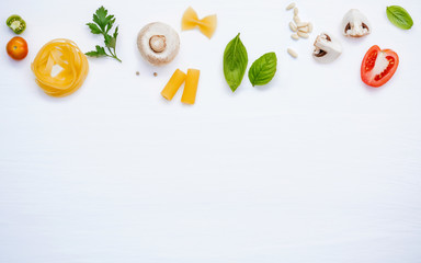Various vegetable and ingredients for cooking pasta menu sweet basil ,tomato ,garlic ,extra virgin olive oil ,parsley  and champignon setup on white wooden background with copy space.