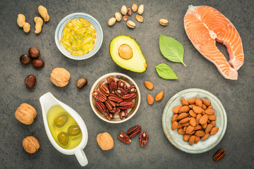 Selection food sources of omega 3 and unsaturated fats. Superfood high vitamin e and dietary fiber for healthy food. Almond ,pecan,hazelnuts,walnuts,olive oil,fish oil and salmon on stone background.