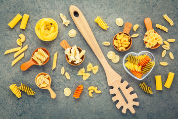Italian foods concept and menu design. Various kind of Pasta Farfalle, Pasta A Riso, Orecchiette Pugliesi, Gnocco Sardo and Farfalle in wooden spoons setup on stone background with flat lay.