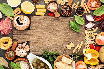 Italian food cooking ingredients on dark stone background with cutting board flat lay and copy space.