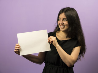 Naklejka premium Surprised Young Brunette Girl holding empty blank white board. Leaflet presentation. Pamphlet hold hands. Girl show clear offset paper. Sheet template. Booklet design sheet display read first person.